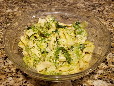 Finished mustard cole slaw served in a clear bowl.