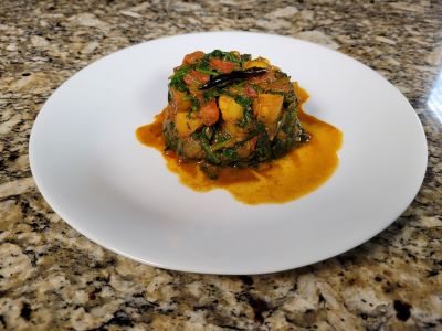 Finished potato and spinach curry served on a white plate.